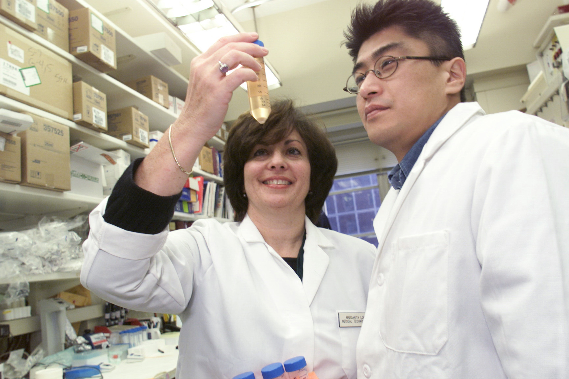 Two scientists examining a vial together at an NCI laboratory.