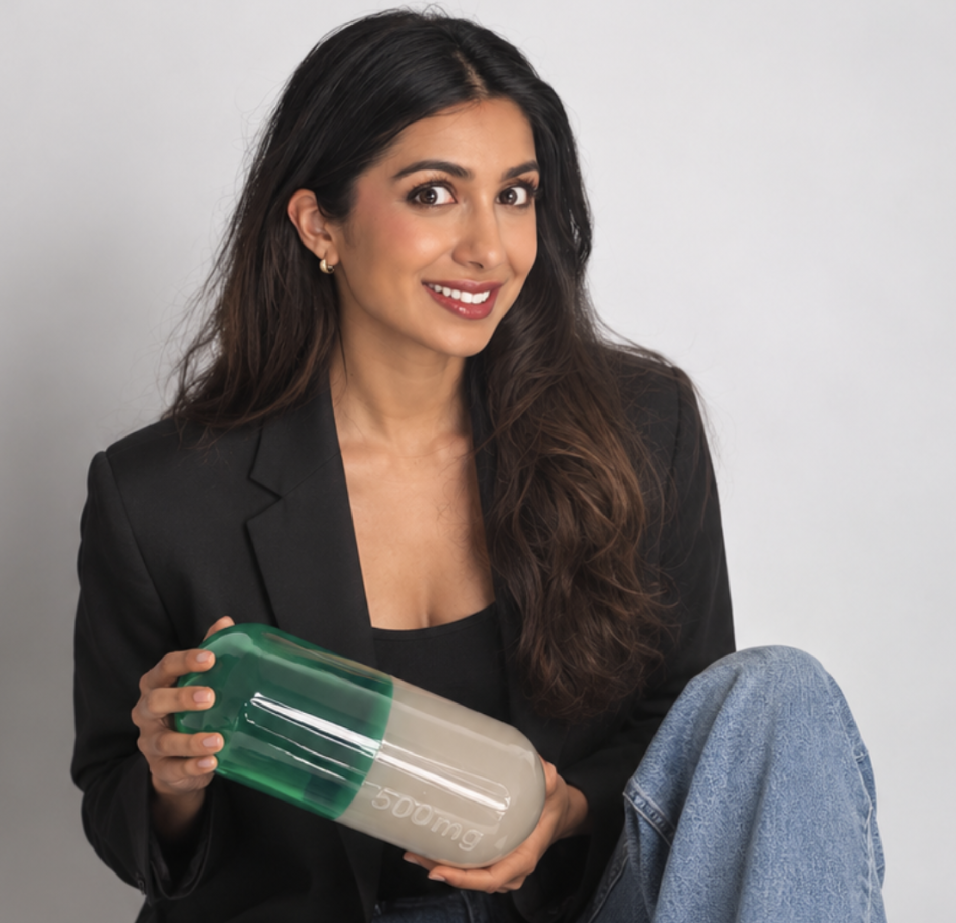 Deeya Kotecha, founder of The New Alchemist, holding a green and ivory capsule sculpture.